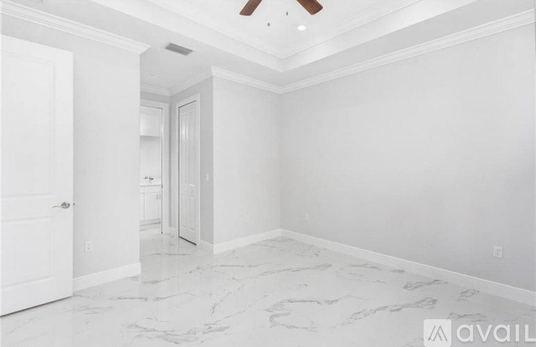 A spacious room with a marble floor and a ceiling fan.