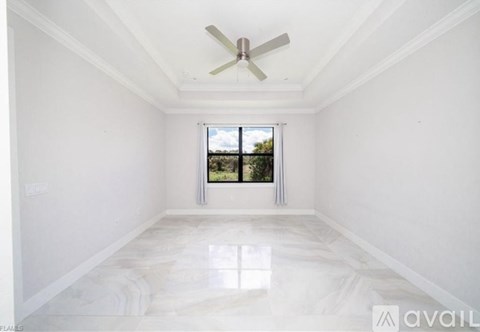 A spacious room with a marble floor and a ceiling fan.