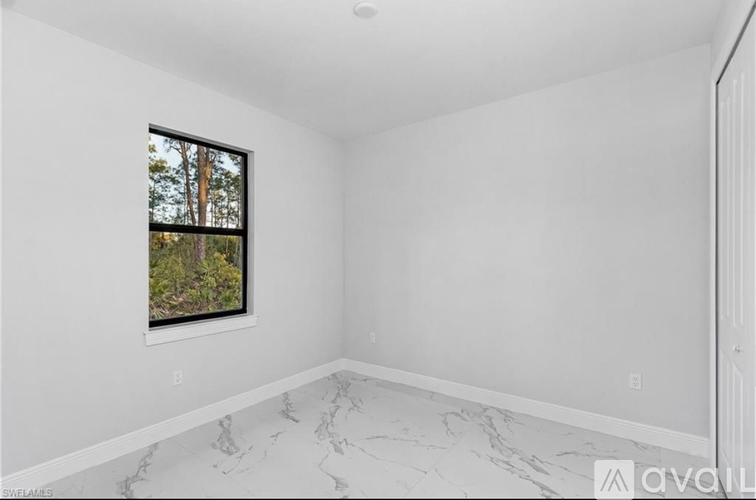 A room with a marble floor and a window showing trees outside.