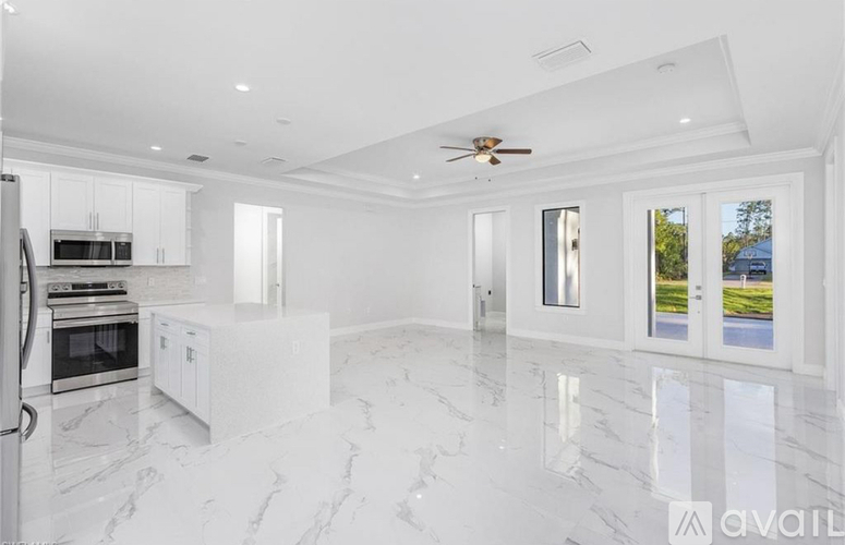 A spacious kitchen with white cabinets and marble flooring.