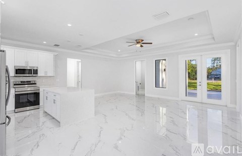 A spacious kitchen with white cabinets and marble flooring.