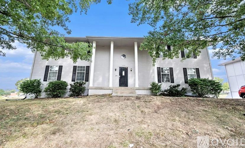 A house with a front yard and trees in the background.