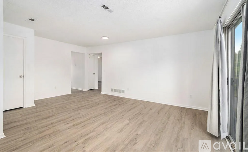 A spacious room with wooden flooring and white walls.