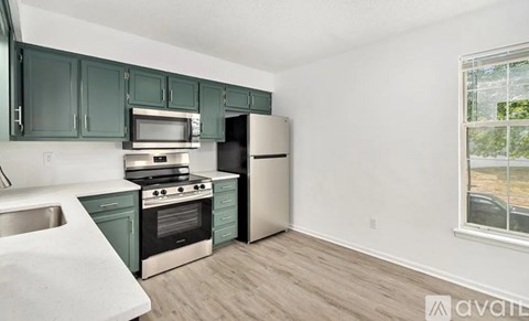 A kitchen with green cabinets and stainless steel appliances.