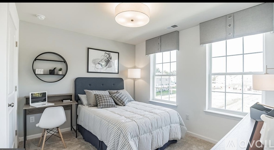A bedroom with a bed, desk, and chair.