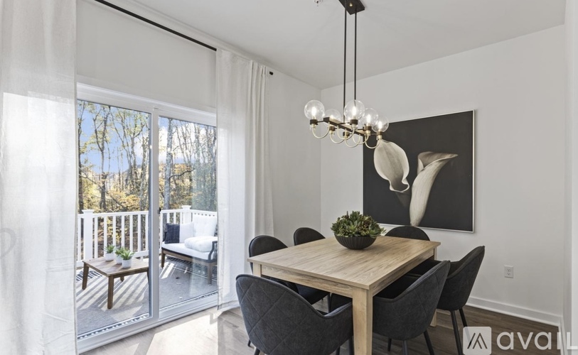 A dining room with a wooden table and chairs, a chandelier, and a view of a deck through the sliding glass doors.