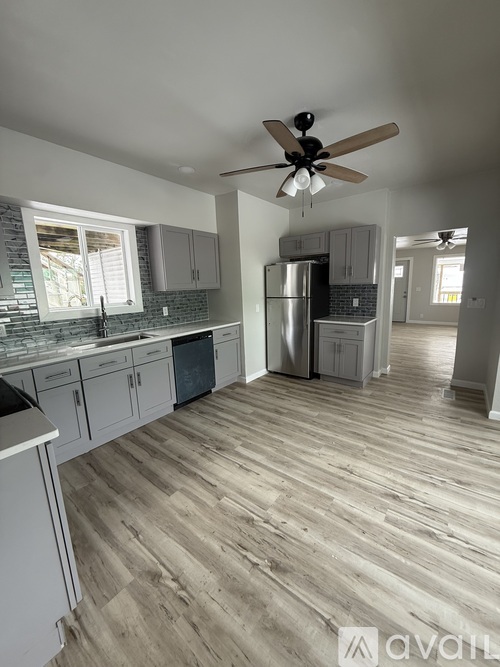 A kitchen with wooden floors and a ceiling fan.