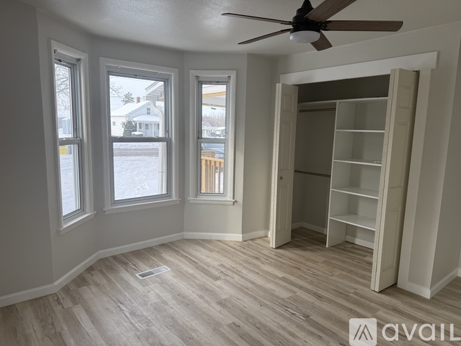 A room with a fan, shelves, and windows overlooking a snowy street.