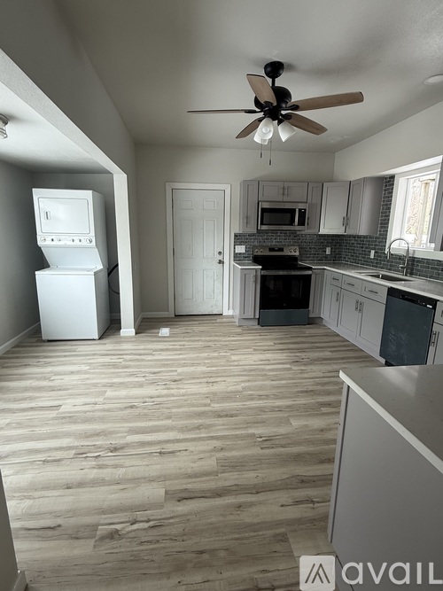 A kitchen with a white fridge and wooden floors.