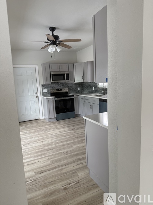 A kitchen with a fan on the ceiling and wooden flooring.
