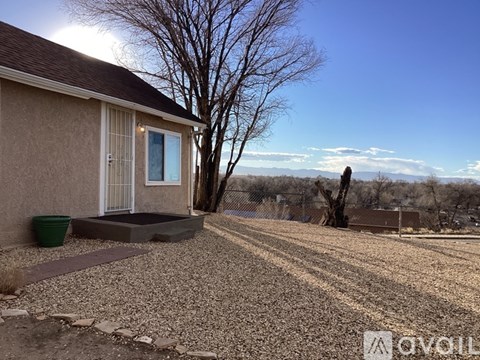 A house with a gravel driveway and a tree in front.