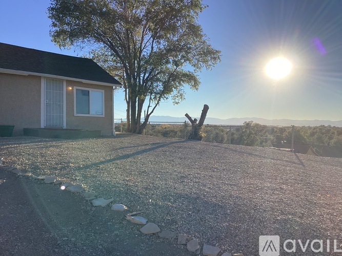 A house with a gravel driveway and a tree in the background.