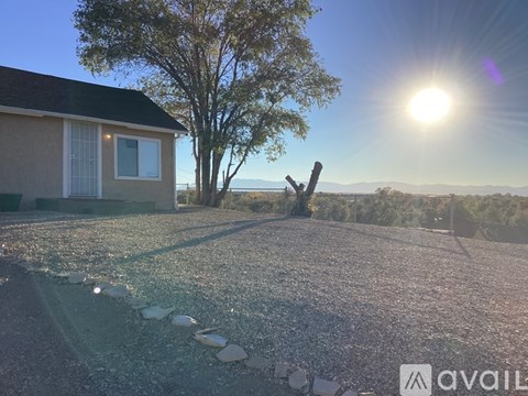 A house with a gravel driveway and a tree in the background.