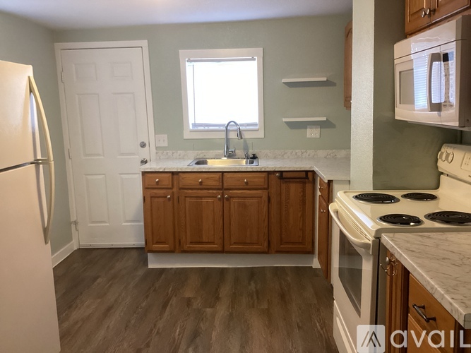 A kitchen with wooden cabinets and a white stove top oven.
