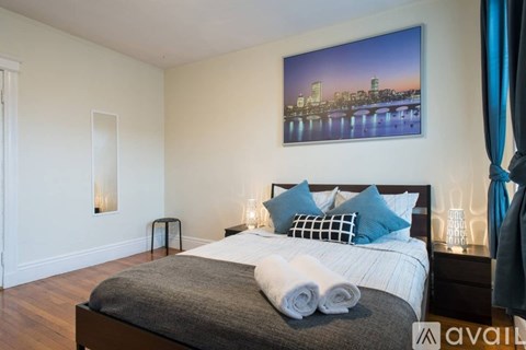 A bedroom with a large bed and a picture of a city skyline on the wall.