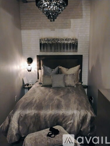 A bedroom with a bed, a chandelier, and a wall-mounted shelf with plants.