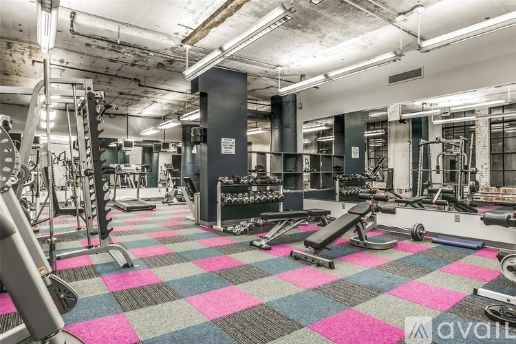 A gym with a variety of equipment including treadmills, weights, and exercise machines.