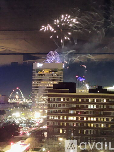 A cityscape at night with a large building and fireworks in the sky.
