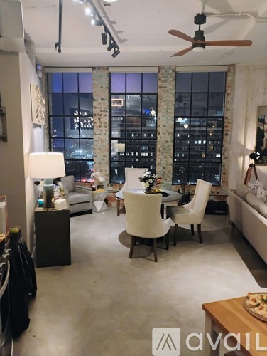 A living room with a couch, chairs, and a table with a pizza on it.