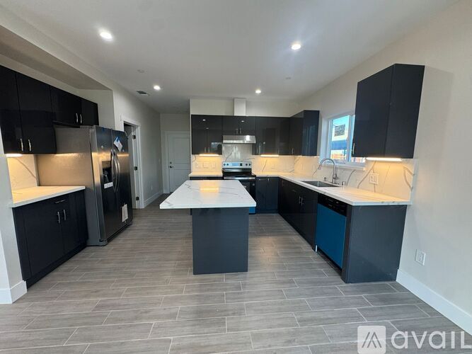 A modern kitchen with black cabinets and a central island.
