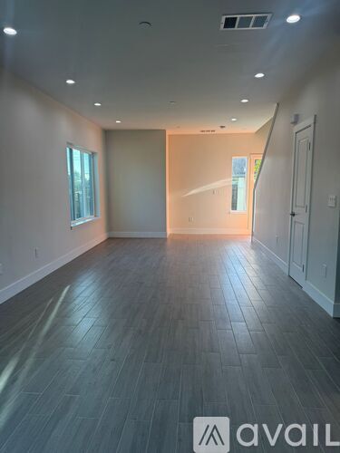 A room with wooden flooring and a window on the left side.