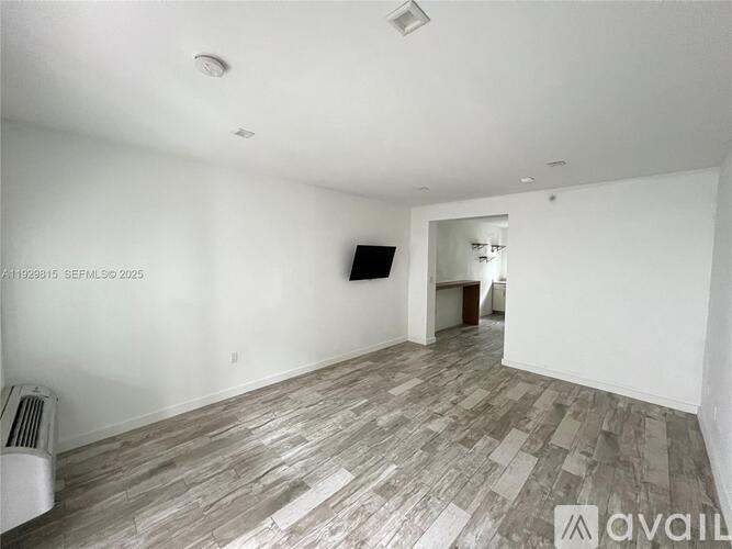 A room with wooden flooring and a flat screen TV mounted on the wall.