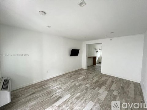 A room with wooden flooring and a flat screen TV mounted on the wall.