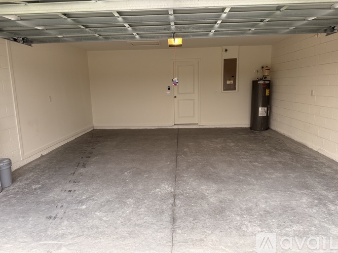 A spacious garage with a concrete floor and a white door.