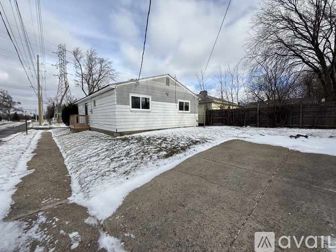 A house with a grey roof and a fence in the snow.