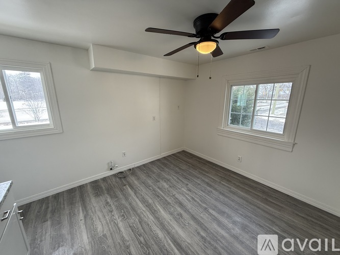 A room with a ceiling fan and two windows.