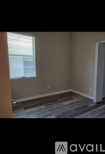 A room with a wooden floor and a window with blinds.