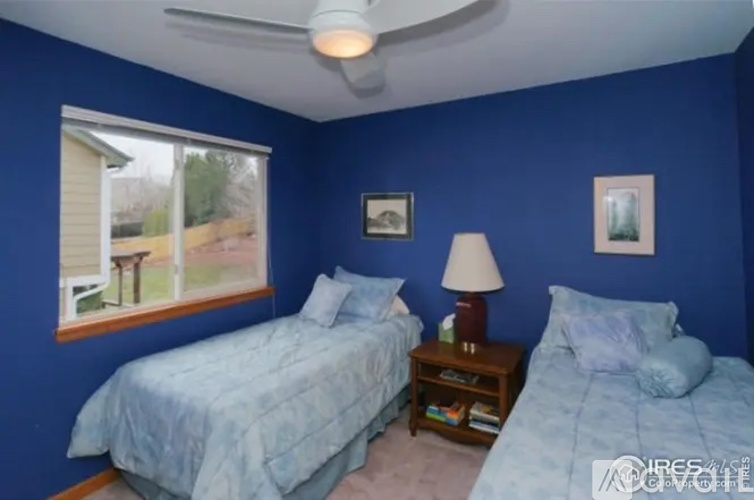 A bedroom with two beds and a ceiling fan.