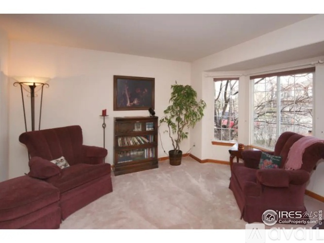 A living room with two red chairs and a bookshelf.