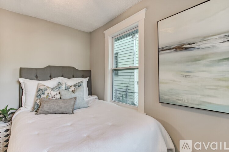A bedroom with a large bed and a painting on the wall.