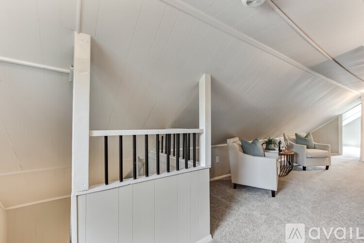 A living room with a white couch and a staircase.
