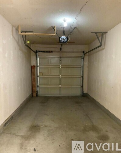 A spacious garage with a closed white door and a hanging light fixture.