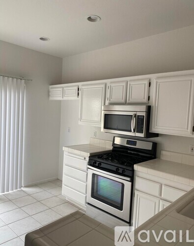 A kitchen with white cabinets and appliances.