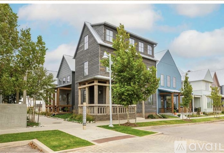 A modern house with a large front porch and a well-maintained lawn.