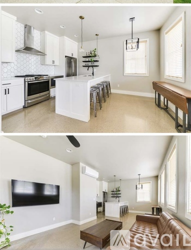 A modern kitchen with white cabinets and a black television in the living room.