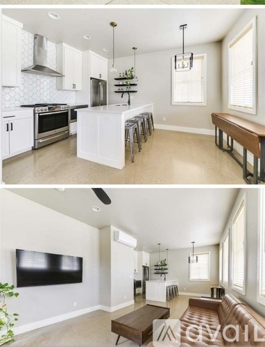 A modern kitchen with white cabinets and a black television in the living room.