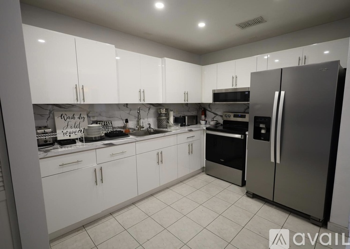 A kitchen with white cabinets and a stainless steel refrigerator.