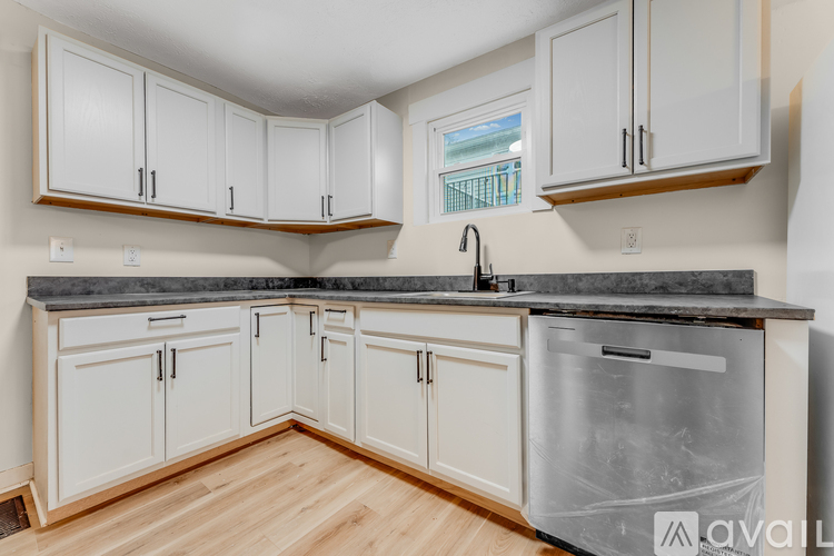 A kitchen with white cabinets and a black countertop.