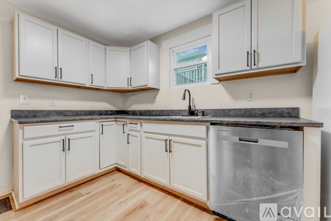 A kitchen with white cabinets and a black countertop.