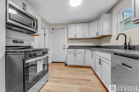 A kitchen with white cabinets and a wooden floor.