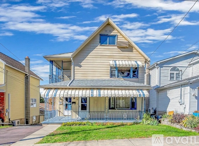 A two-story house with a striped awning on the front porch.