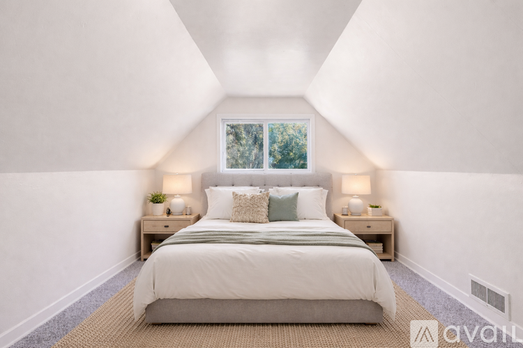 A bedroom with a large bed and two lamps on either side.