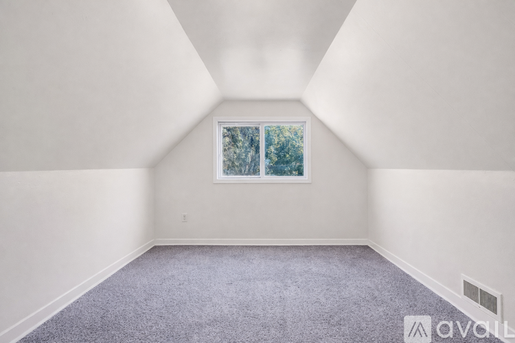 A room with a carpeted floor and a window showing trees outside.