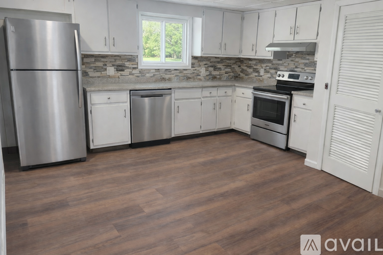 A kitchen with white cabinets and a wooden floor.