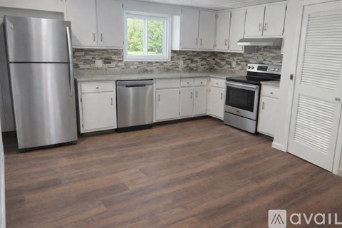 A kitchen with white cabinets and a wooden floor.