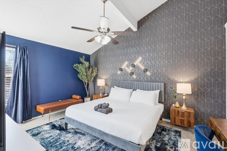 A bedroom with a white bed and a ceiling fan.